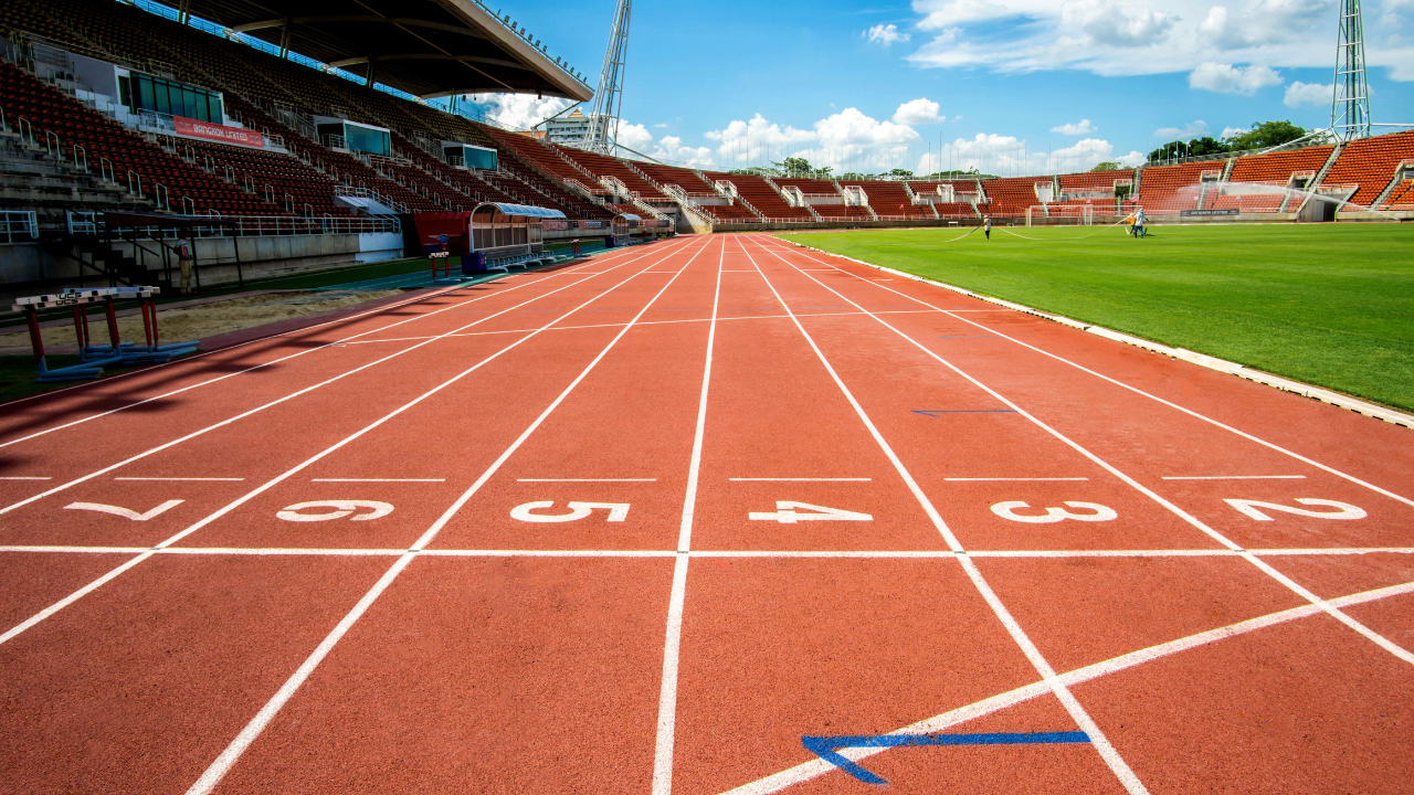 Close-up of a modern athletic track with athletes running, highlighting the advanced material and texture of the track surface.