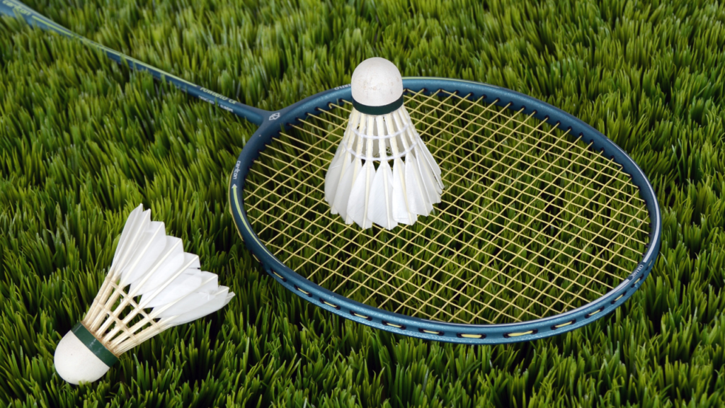 Close-up of a badminton racket with a shuttlecock, showcasing the racket's strings and grip.