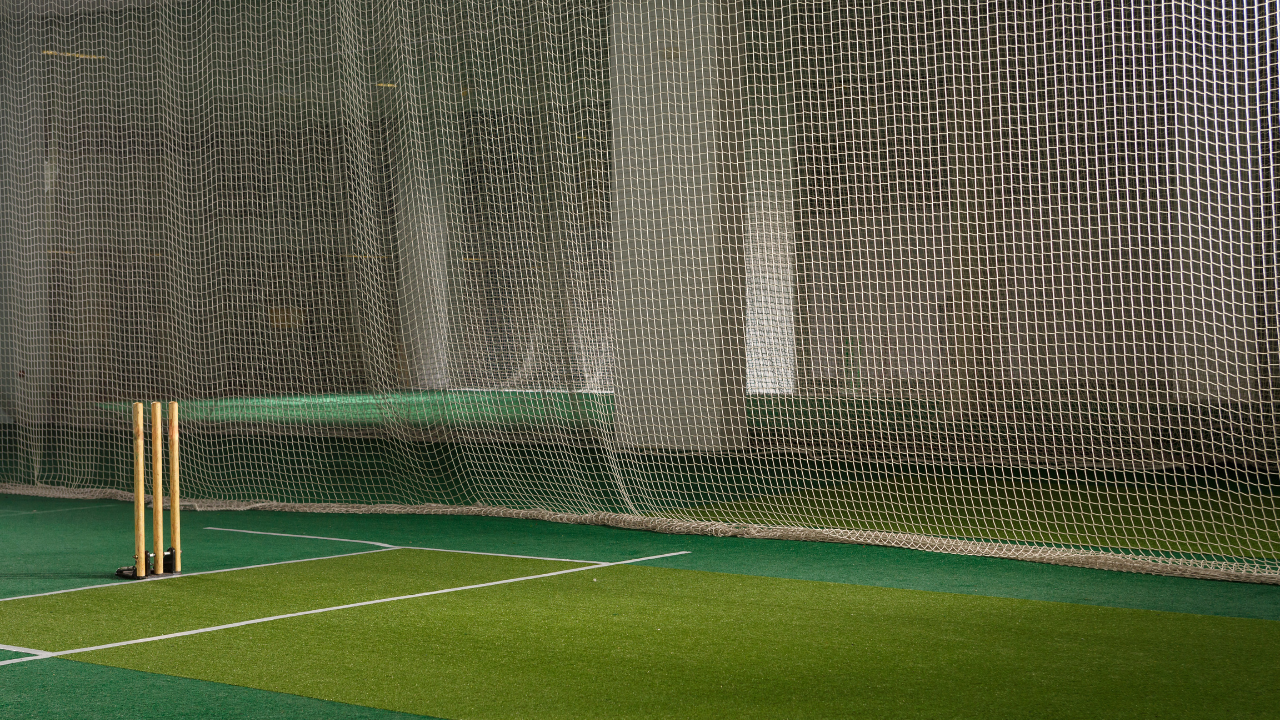 Person setting up a cricket net in the garden, showcasing the best options for home use.