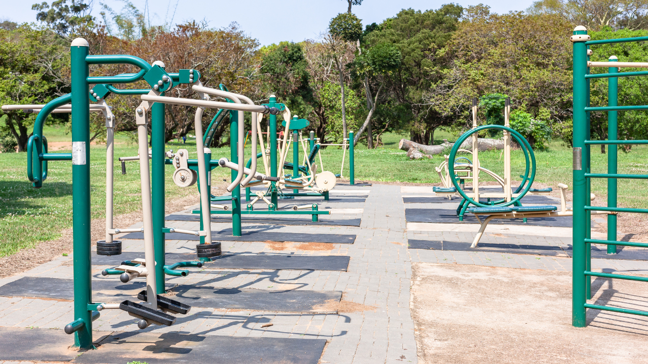 Outdoor gym setup with equipment in a sunny park, ideal for summer workouts.