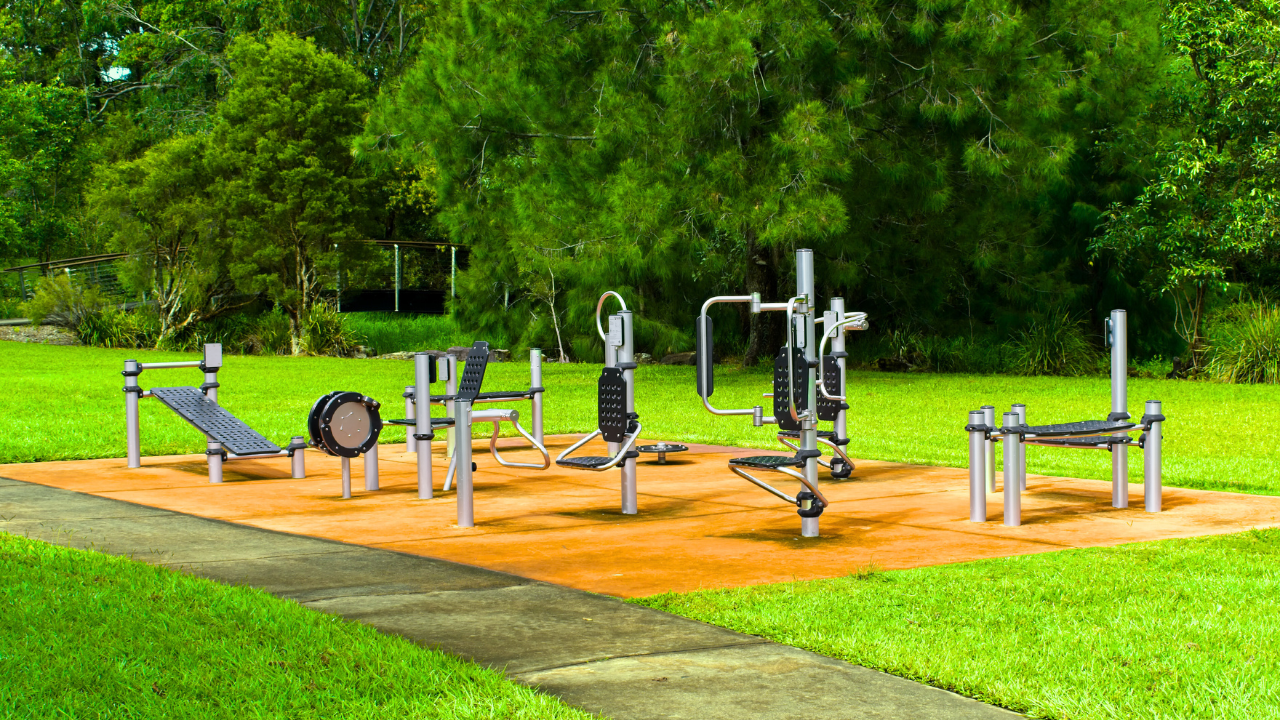 Person using outdoor gym equipment in a park setting for fitness training.