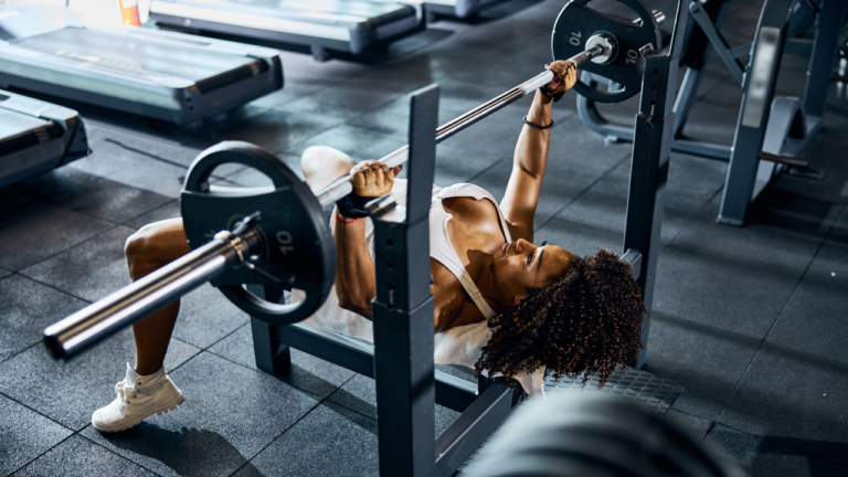 Man performing incline bench press with a barbell in the gym for upper body strength.