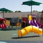 Children playing on colorful, safe play equipment in a park or playground.