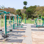 An outdoor gym setup in a park, featuring workout equipment designed for community use and sports facilities.