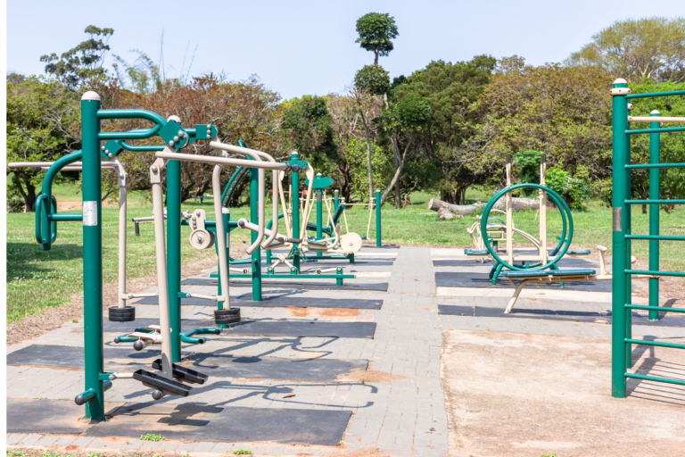 An outdoor gym setup in a park, featuring workout equipment designed for community use and sports facilities.