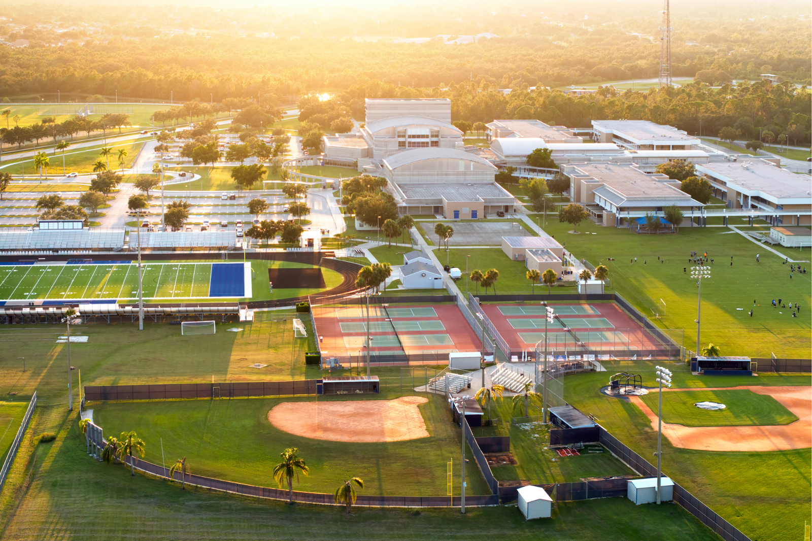 A school sports facility showing a well-maintained outdoor field and an indoor sports hall with various equipment.