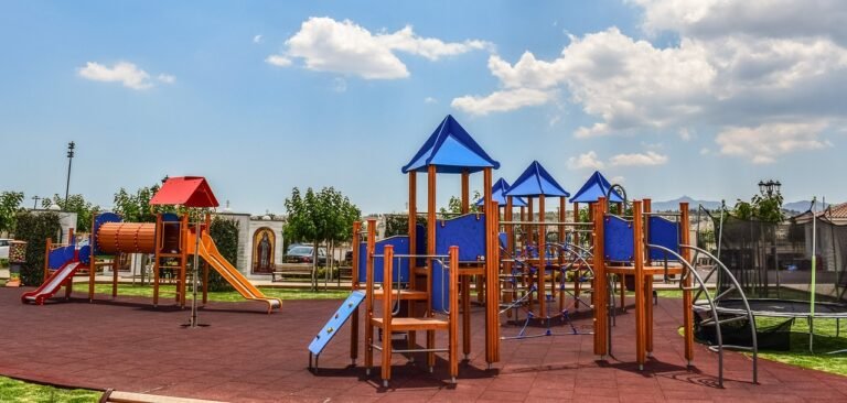 A vibrant playground featuring modern equipment like climbing structures, swings, and interactive play panels.