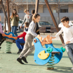 A colorful playground with children playing safely under adult supervision, surrounded by safety features like soft flooring and secure equipment.