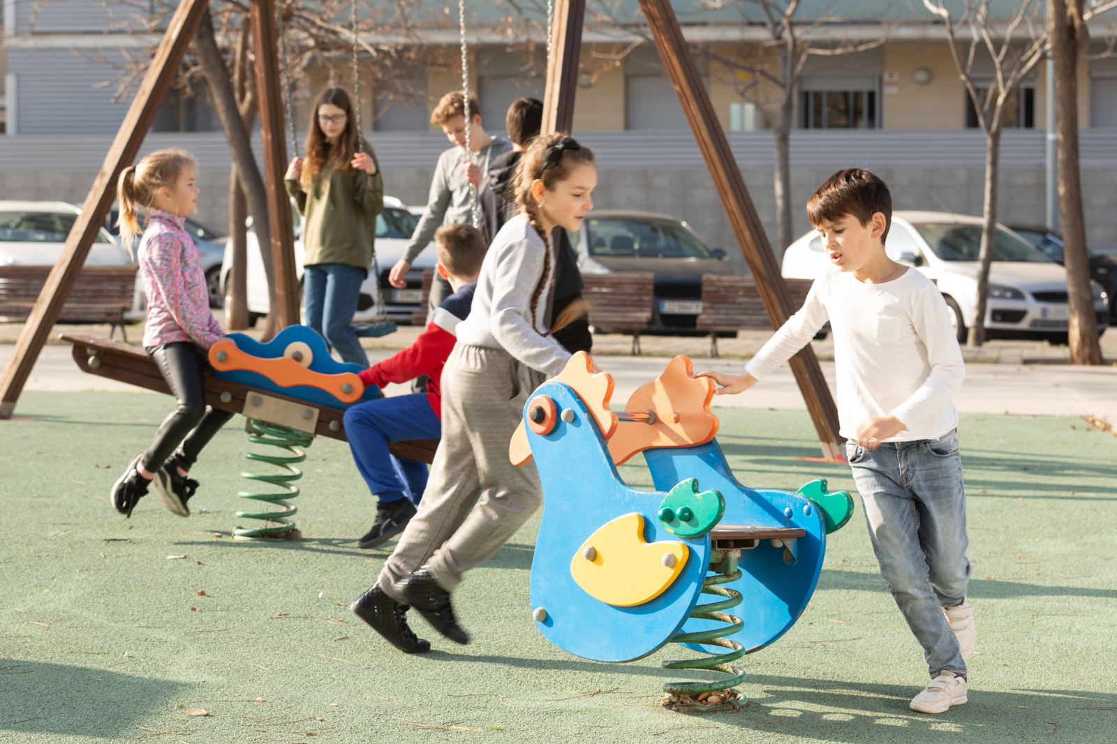 A colorful playground with children playing safely under adult supervision, surrounded by safety features like soft flooring and secure equipment.